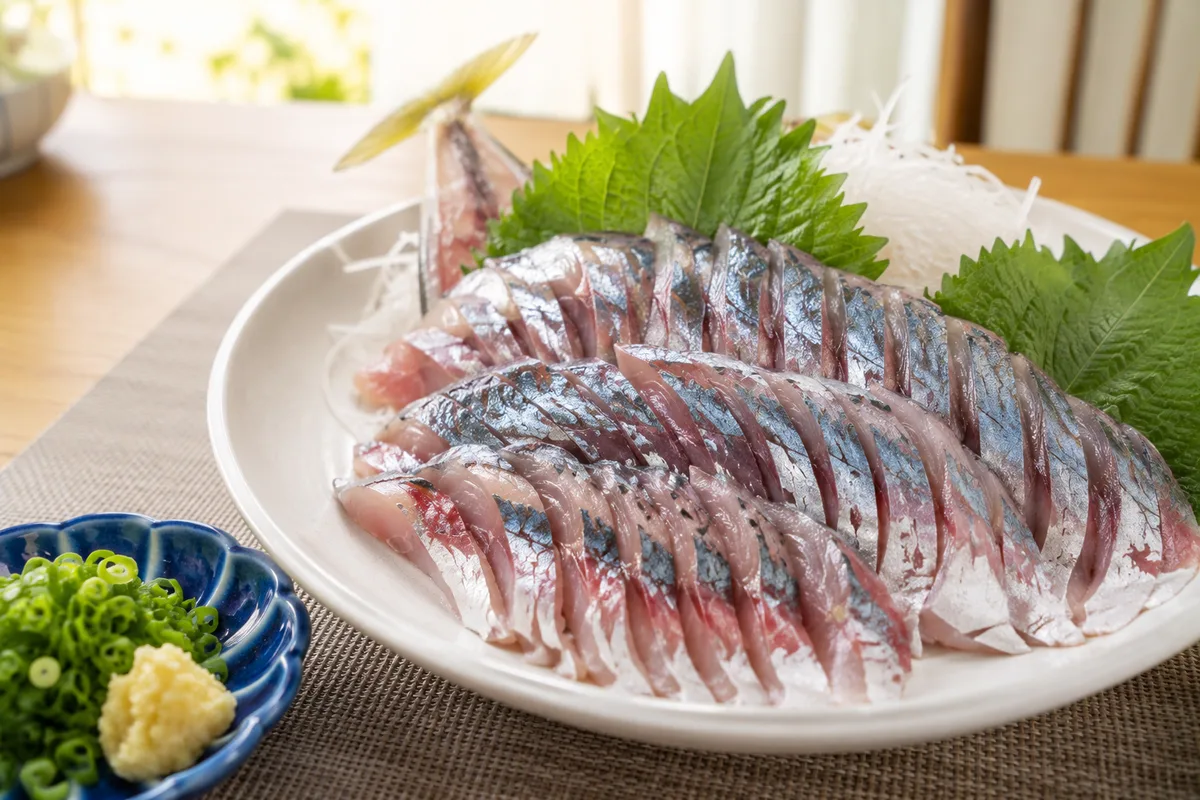 釣りたての大アジ（尺クラス）を三枚におろした刺身が白い和皿に美しく盛り付けられた様子。脂の乗った身の照りが分かる