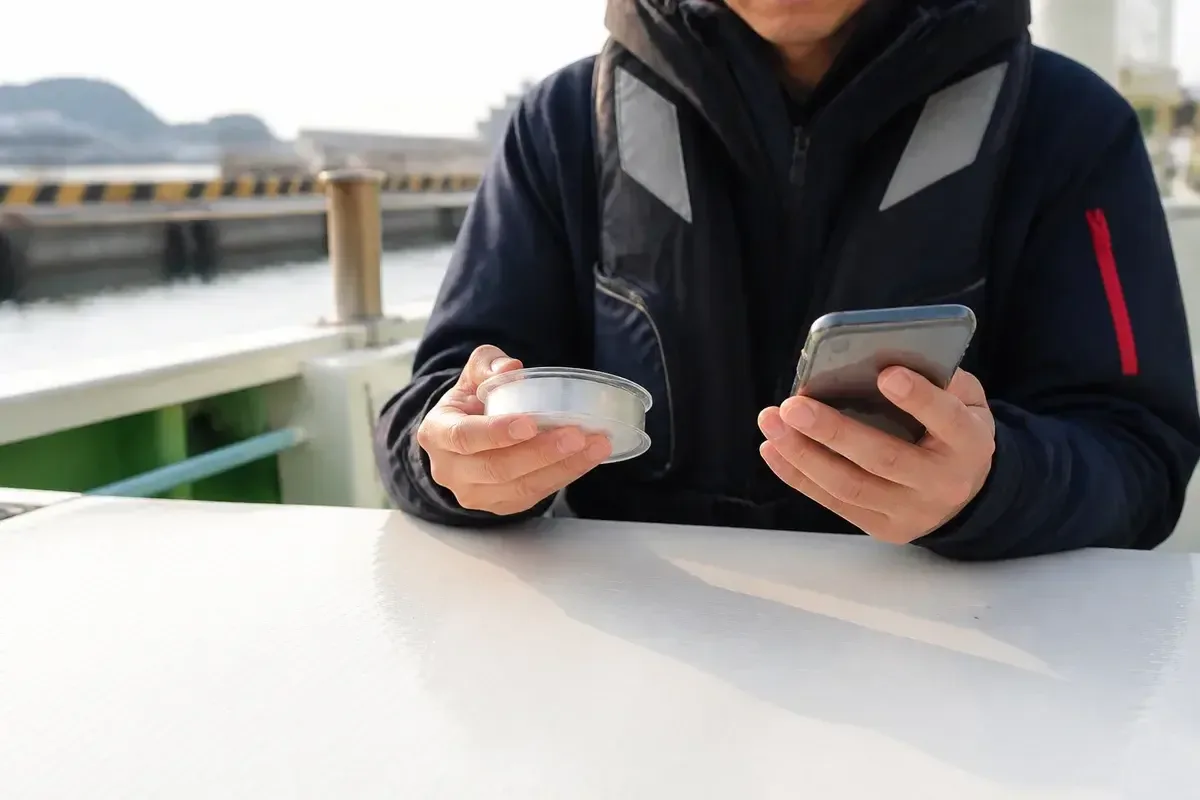 出船前に船宿の案内と無地のハリススプールを照合する釣り人