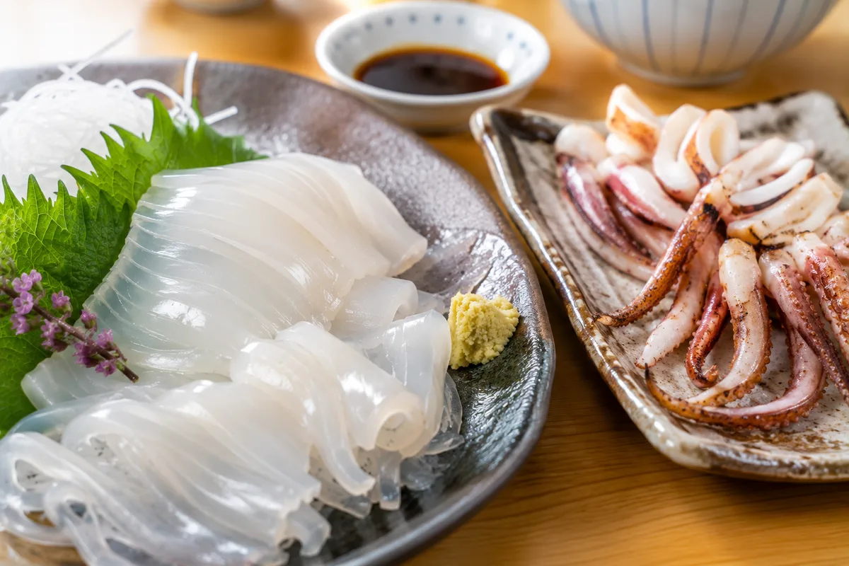 釣りたてマルイカの刺身とげそ焼きが並ぶ食卓。透明感のある白身が美しい料理写真