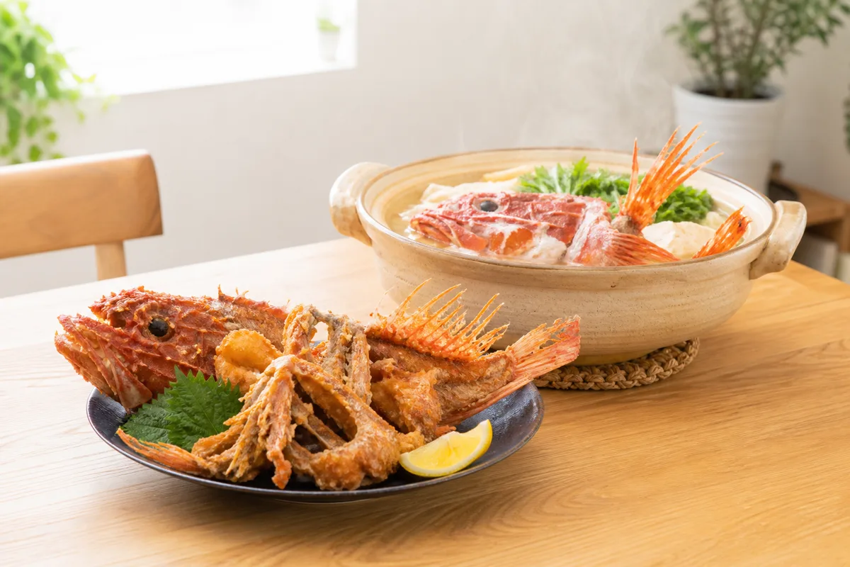 オニカサゴのから揚げが並ぶ食卓。骨まで香ばしく揚がった一皿と湯気の立つ鍋料理が印象的な写真