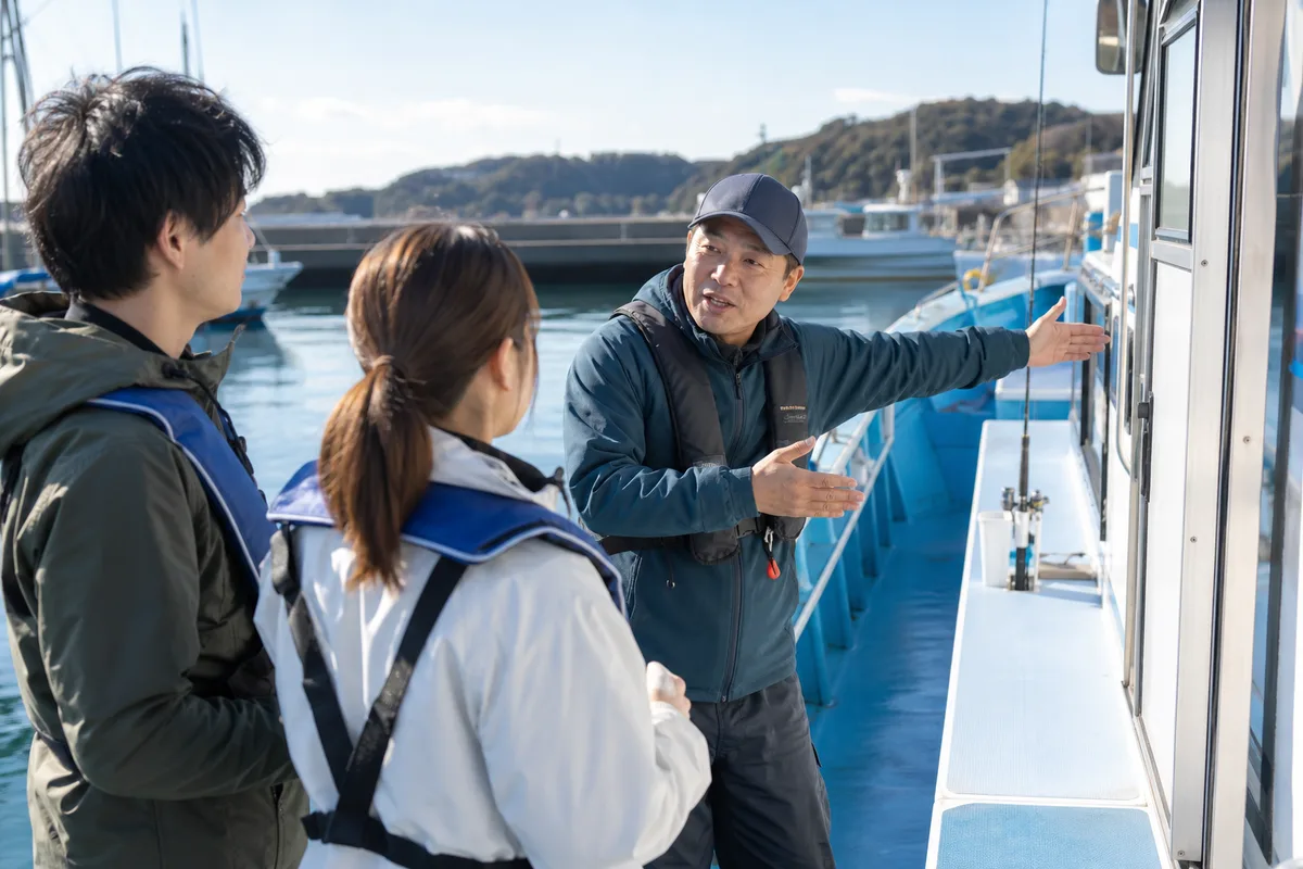 出船前の港で、乗船者が船長に当日の海況と過ごしやすい場所を相談している様子
