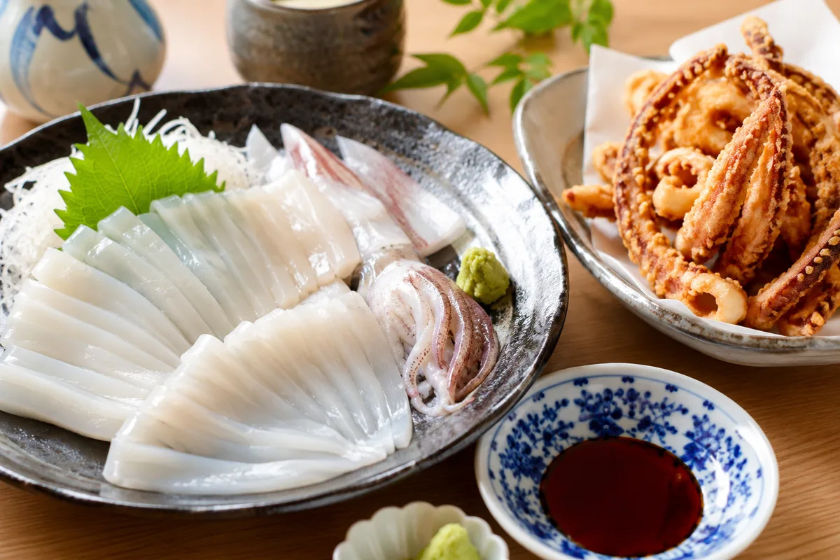 釣りたてスルメイカの刺身とゲソ揚げが並ぶ食卓。艶やかな白身と炭焼きのゲソ